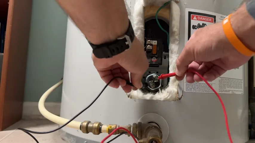 Multimeter probes held against an electric water heater heating element